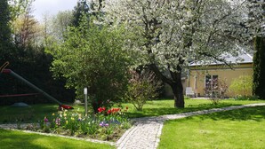 A garden with a cobblestone path, flowering plants, and a playground.
