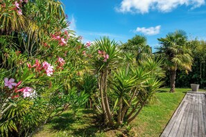 Un jardín con diversas plantas y una terraza de madera.