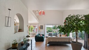A spacious bedroom with a large bed, a green sofa, and a potted tree.