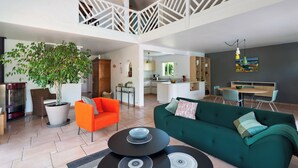 A spacious living area with a high ceiling, a dining area, and a kitchen.