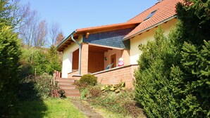 Een huis met een bakstenen gevel, een houten veranda en een rode pannendak.