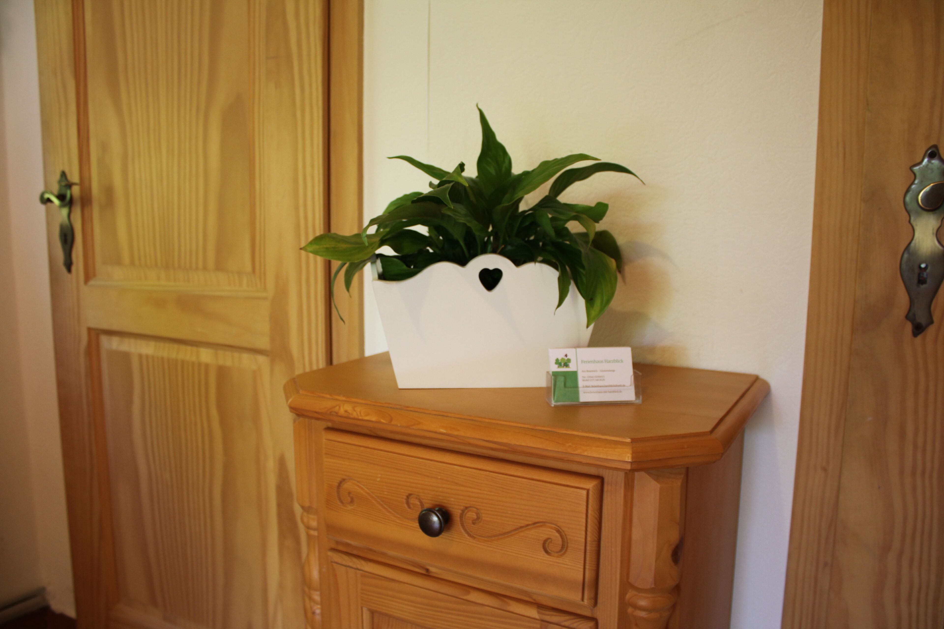 Een houten dressoir met een plantje erboven en een klein kaartje ernaast.