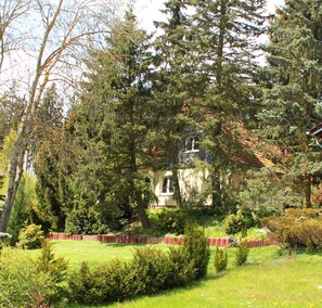 A house surrounded by dense trees and a well-maintained lawn. - -> Holiday home Harzblick <- Fantastic view over the Harz mountains (Güntersberge)
