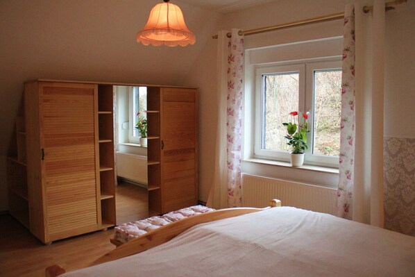 A bedroom with a bed, wooden wardrobe, and a window with a potted plant. - -> Holiday home Harzblick <- Fantastic view over the Harz mountains (Güntersberge)