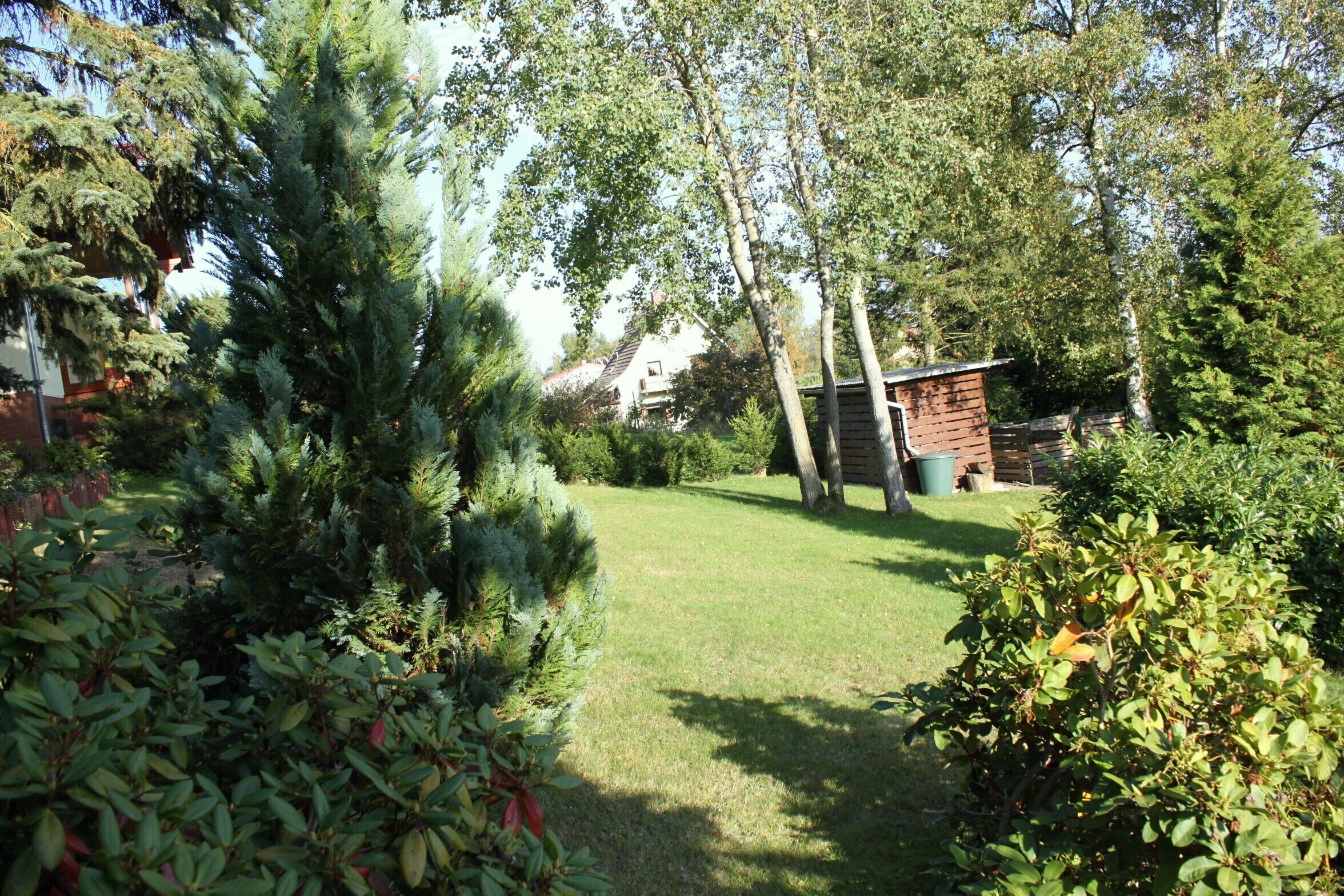 Un jardín con césped, árboles y una construcción de ladrillo.