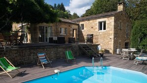 Un edificio de piedra con piscina y zona de estar al aire libre.