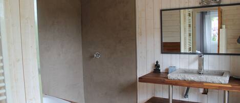 A bathroom with a wooden vanity, a white bathtub, and a shower area.