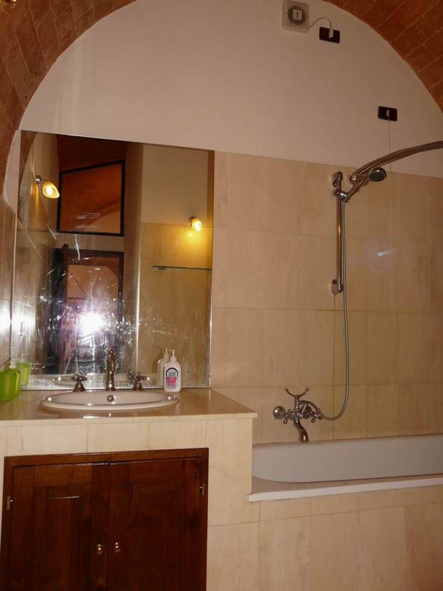 Ein Badezimmer mit großem Spiegel, Waschbecken, Dusche und Holztür.