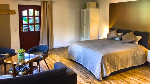 Un dormitorio con cama, armario, escritorio con silla y ventana con cortinas.
