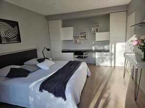 Ein modernes Schlafzimmer mit einem großen Bett, einem Schreibtisch und einer Küchenzeile.