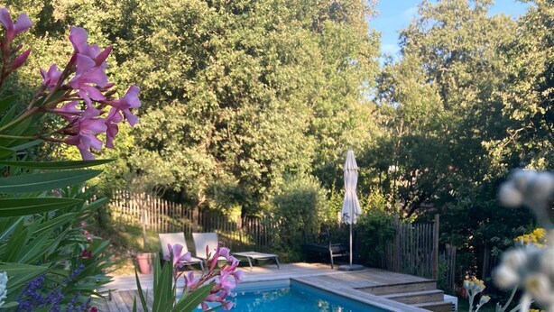 Une piscine entourée d’une terrasse en bois, avec une clôture en bois et des arbres en arrière-plan.