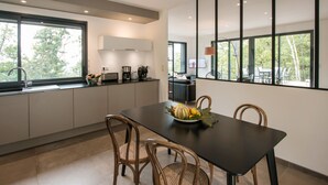 Une cuisine moderne avec une table à manger, des chaises et un panier de fruits.