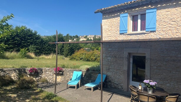 A stone house with a balcony, two lounge chairs, a table with chairs, and a bottle of wine. - Cottage rental at the foot of Mont Ventoux, surrounded by lavender cyclist (Sault)