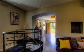 A spacious living area with a staircase, a sofa with cushions, and a view of the outdoors. - 700 meters from the ocean, House with volleyball, pétanque, badminton, ping-pong, and swings (Santa-Lucia-Di-Moriani)