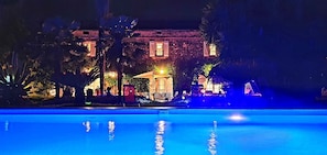 A nighttime view of a pool area with a building in the background. - 700 meters from the ocean, House with volleyball, pétanque, badminton, ping-pong, and swings (Santa-Lucia-Di-Moriani)