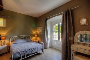 A bedroom with a bed, bedside lamps, a window with curtains, and a chair. - 700 meters from the ocean, House with volleyball, pétanque, badminton, ping-pong, and swings (Santa-Lucia-Di-Moriani)