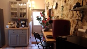 A kitchen with a stone floor, a dining table with chairs, and a red chair. - Restored country house, in the spirit "Countryside" Charm " (Jau-Dignac-et-Loirac)