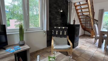 A modern living room with a wooden coffee table, books, a bottle of wine, and a chair.
