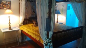 A four-poster canopy bed with a yellow bedspread, two bedside lamps, and a framed photo on the wall. - 4* villa with beautiful garden - 2 to 10 people (Bangor)