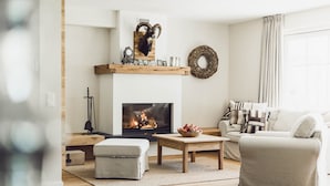 Un salón con chimenea, un sofá, una mesa de centro y un elemento decorativo en la pared.