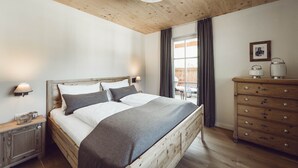 Un dormitorio con una cama de madera, lámparas de noche, un aparador y una ventana con cortinas.