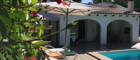 A poolside area with lounge chairs and a covered patio.