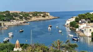 A coastal town with boats docked along the harbor, a lighthouse, and buildings with Mediterranean architecture.