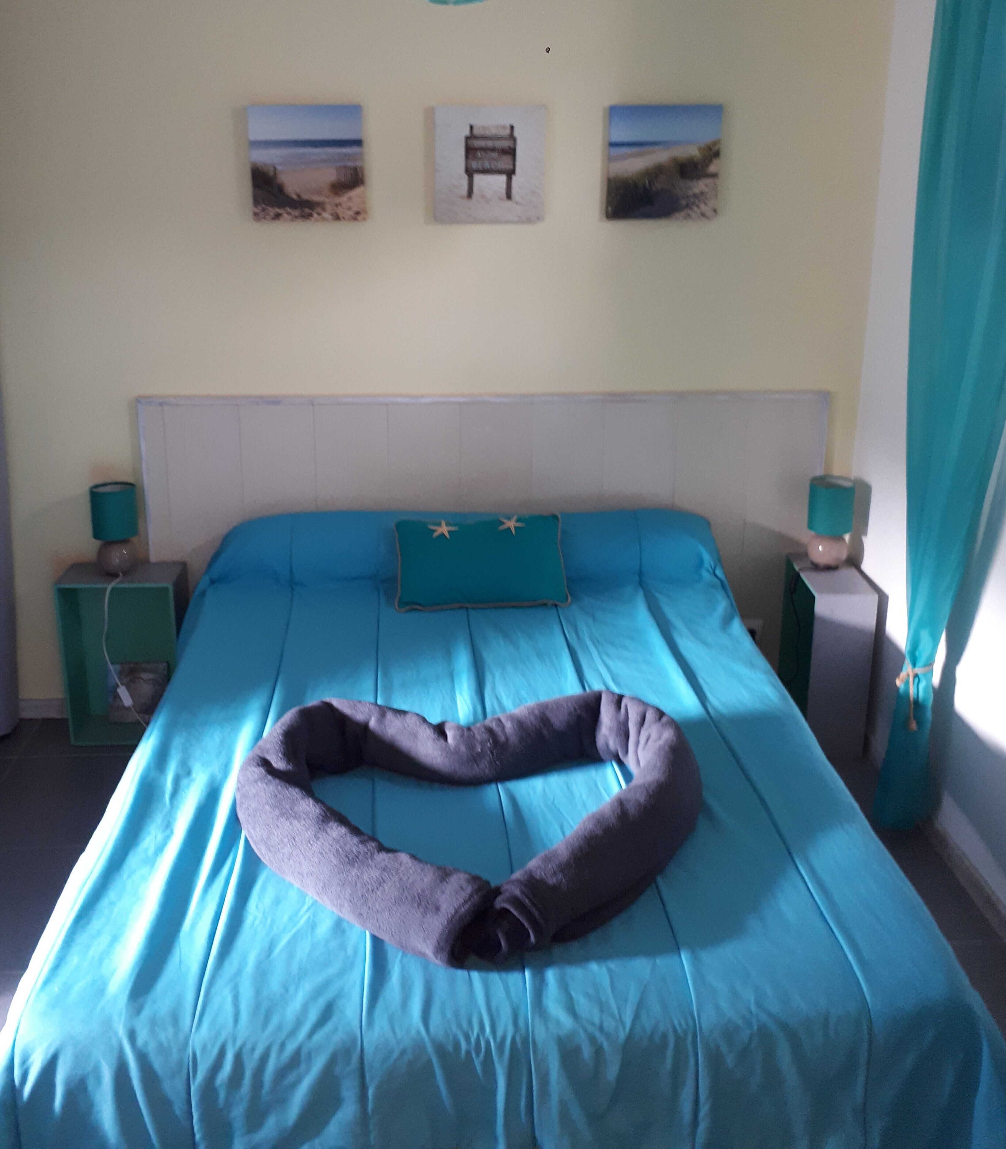 Une chambre à coucher comprenant un lit, deux tables de chevet, une tête de lit et trois tableaux accrochés au mur.