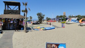 A beach with a wooden structure, inflatable pools, and a sign for Nestle Gold Helados. - Sea View Penthouse with Private Jacuzzi & Huge Terrace – Cala 4 (Calahonda, Costa Del Sol)