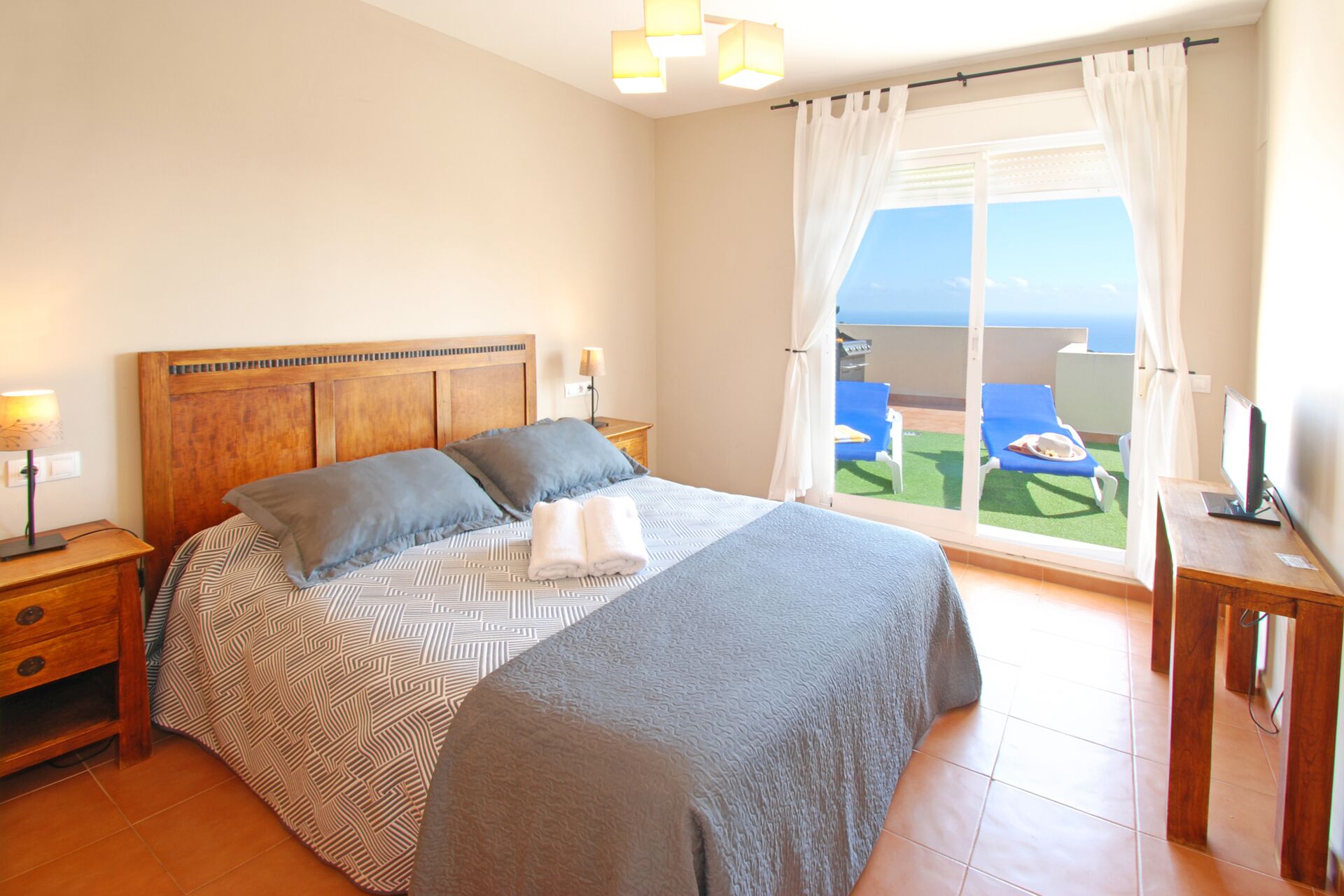 Une chambre à coucher avec un lit, des tables de chevet, un bureau et une vue sur la mer.