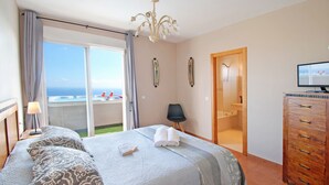 A hotel room with a bed, a TV, a wooden dresser, a chair, and a bathroom with a shower and toilet. - Sea View Penthouse with Private Jacuzzi & Huge Terrace – Cala 4 (Calahonda, Costa Del Sol)