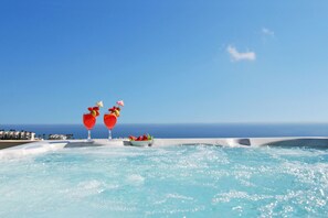 Een hottub met uitzicht op zee en een rij gebouwen op de achtergrond.