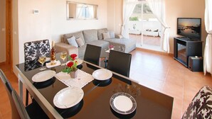 A modern living room with a dining area, a sofa set, a television, and a balcony with outdoor furniture. - Sea View Penthouse with Private Jacuzzi & Huge Terrace – Cala 4 (Calahonda, Costa Del Sol)