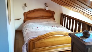 A bedroom with a wooden bed, a wooden ceiling, and a small table with a vase. - Chartreuse Natural Park: cozy nest at the start of hiking trails! (Le Sappey-En-Chartreuse)