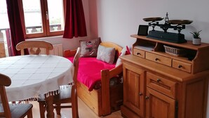 A cozy room with a wooden dining table, a sofa, and a TV mounted on the wall. - Chartreuse Natural Park: cozy nest at the start of hiking trails! (Le Sappey-En-Chartreuse)