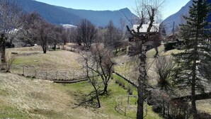 A rural landscape with a fenced field, trees, and mountains in the background. - Chartreuse Natural Park: cozy nest at the start of hiking trails! (Le Sappey-En-Chartreuse)