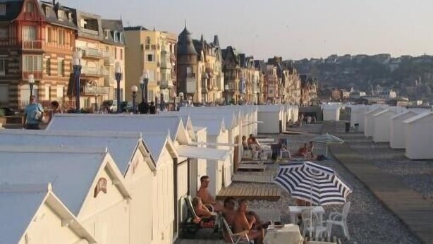 A row of beachside buildings with outdoor seating areas and umbrellas.