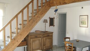 Un escalier avec des rampes en bois menant à un coin repas équipé d’une table et de chaises.
