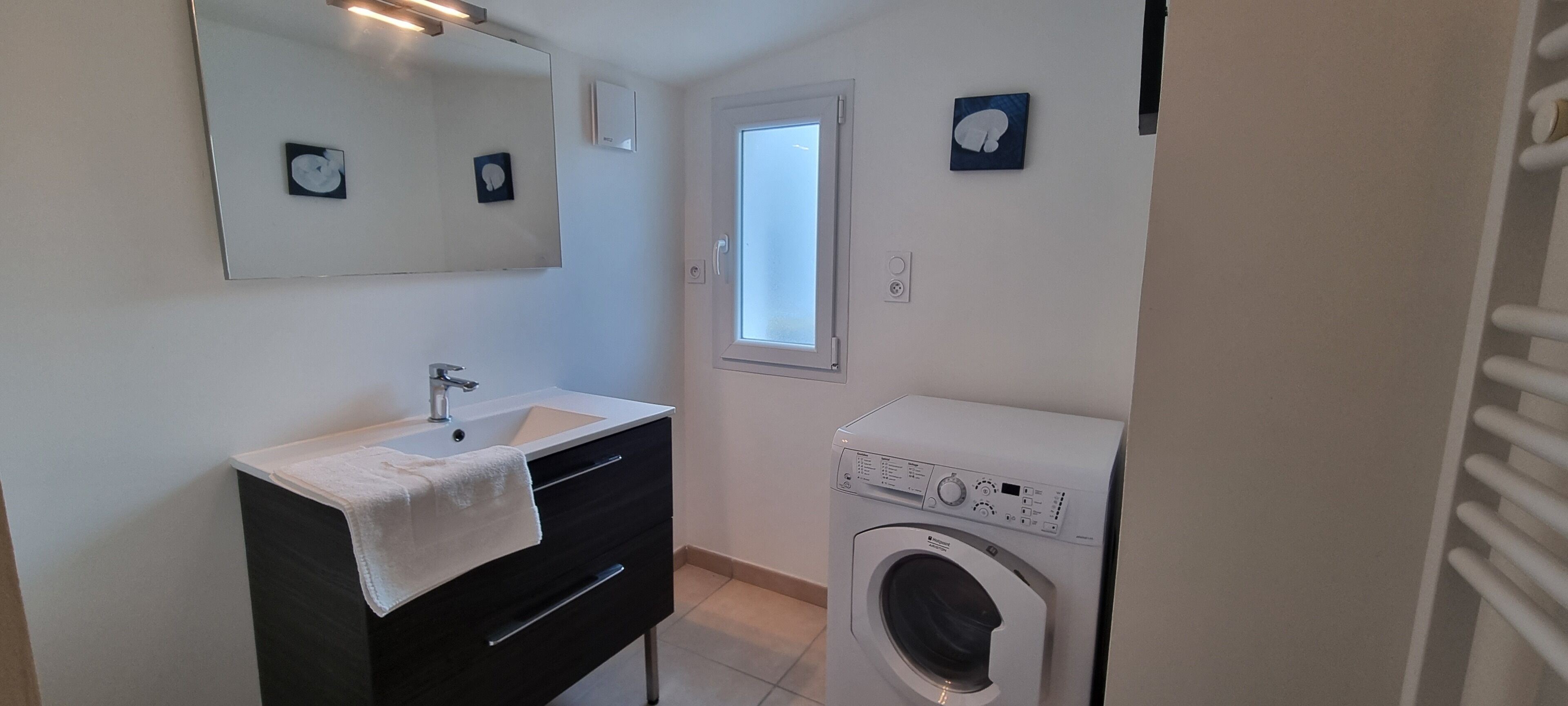 Une petite salle de bain équipée d’un lavabo, d’un miroir et d’un lave-linge à chargement frontal.
