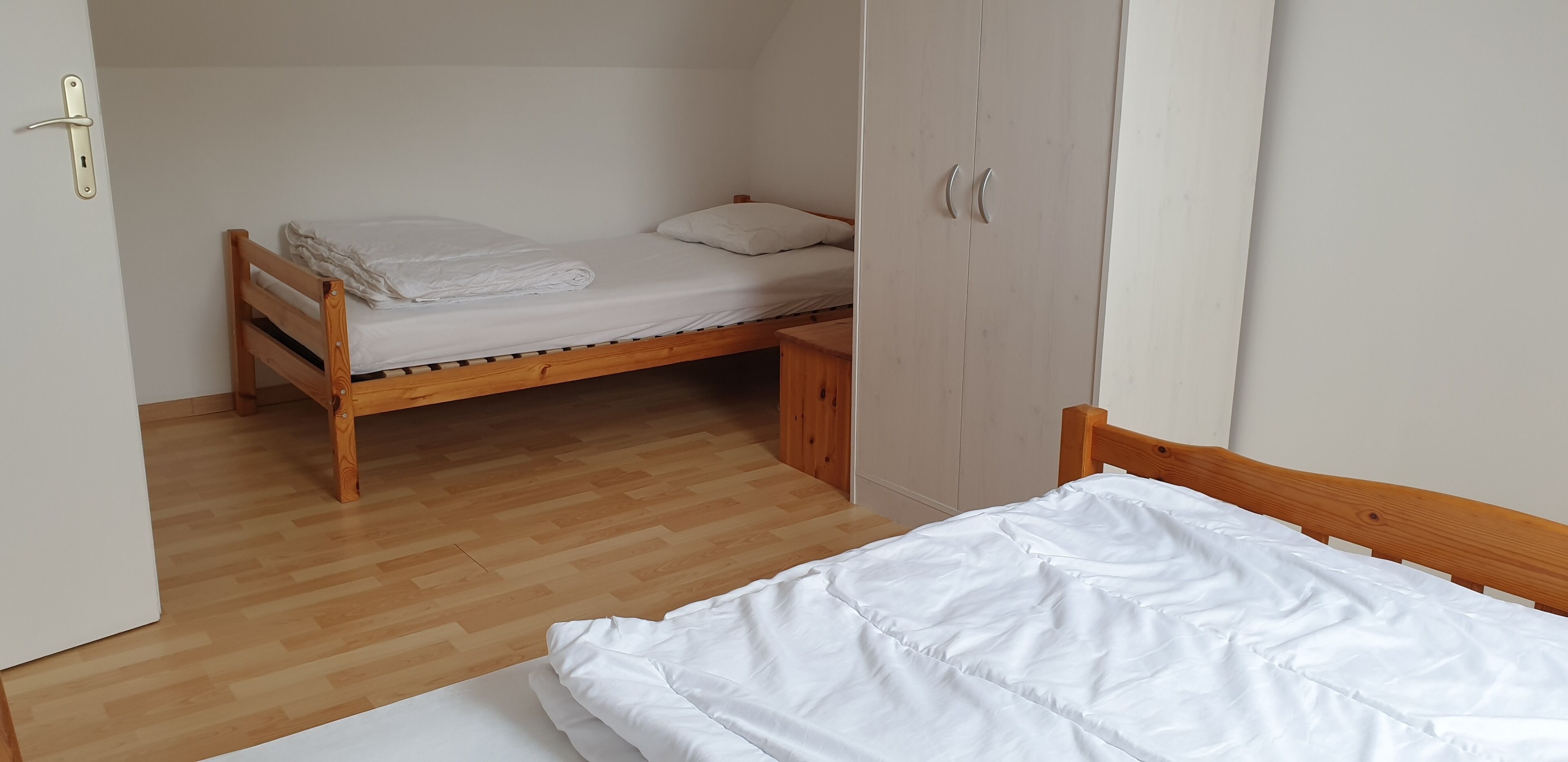 A room with a wooden bed, a wardrobe, and a bench.