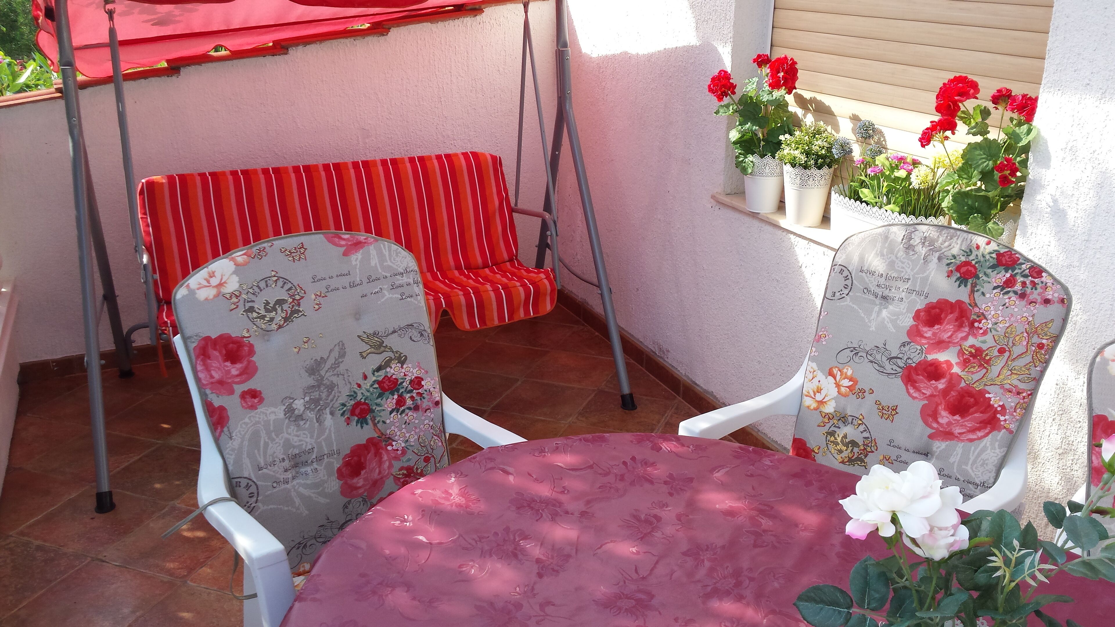 A patio with two chairs, a table, and a red umbrella.