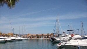 A marina with multiple boats docked, a clear sky, and a brick walkway.