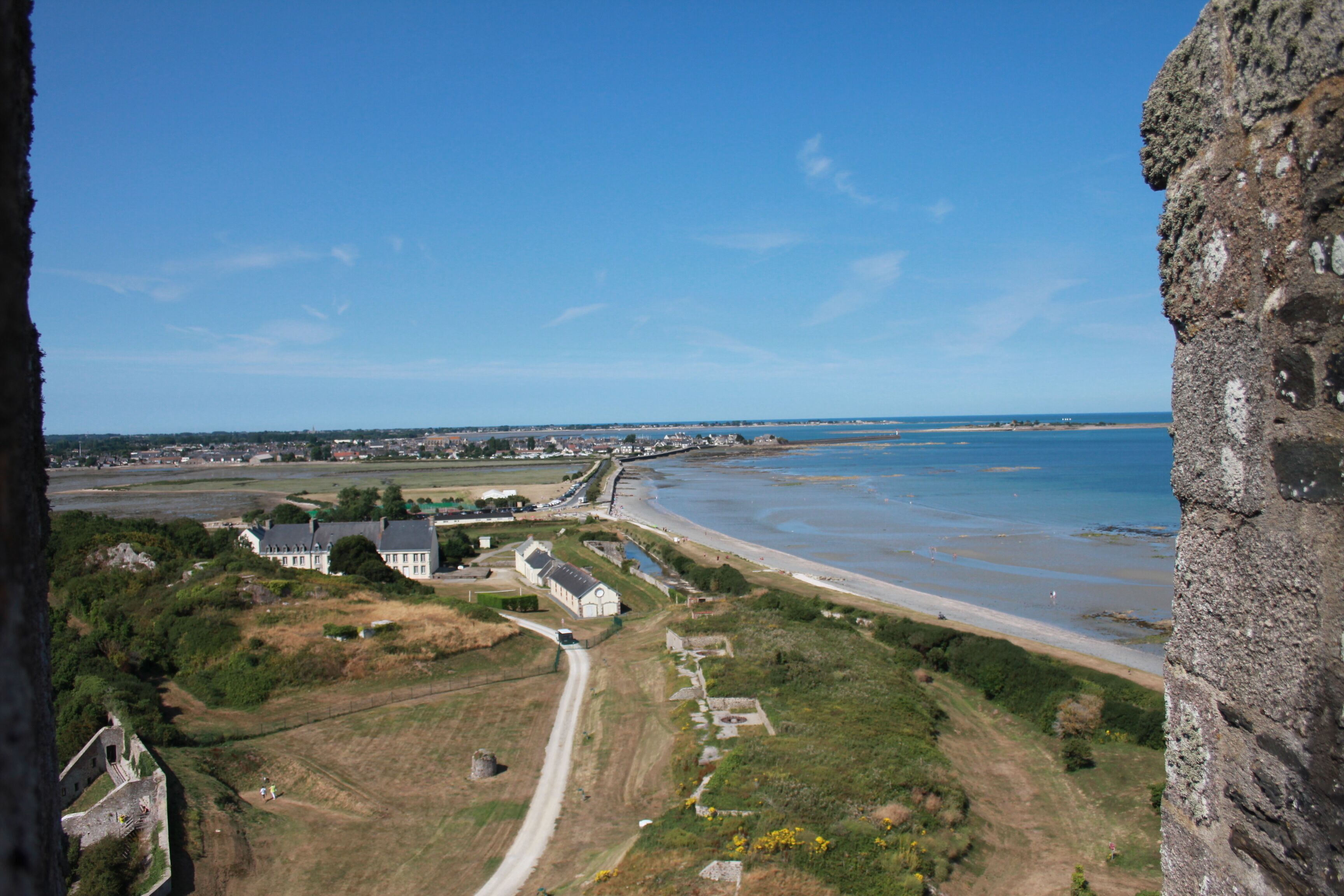 An aerial view of a coastal area with a prominent building, a beach, and a clear sky.