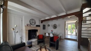 A living room with a fireplace, two armchairs, a sofa, and a dining table.