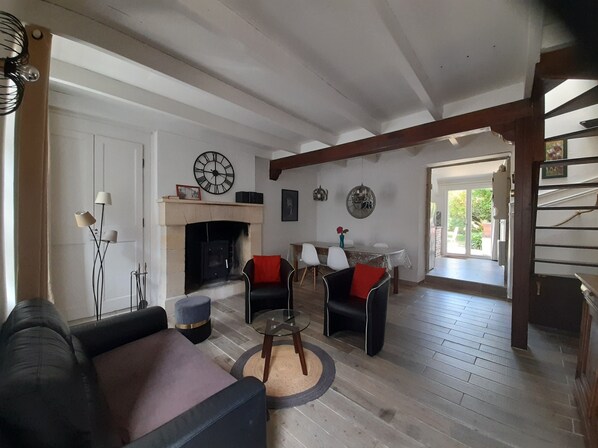 Un salon avec une cheminée, deux fauteuils, un canapé et une table à manger.