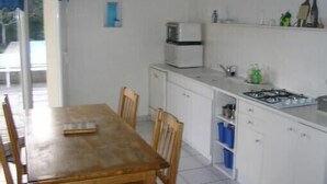 Een compacte keuken met witte kastjes, een kleine koelkast en een gasfornuis.