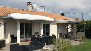 Een overdekte terras met zwembad, tuinmeubels en een tuin.