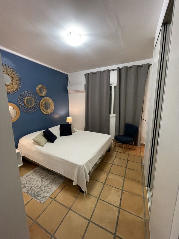 Quarto com cama, uma cadeira, luminária e decorações nas paredes.