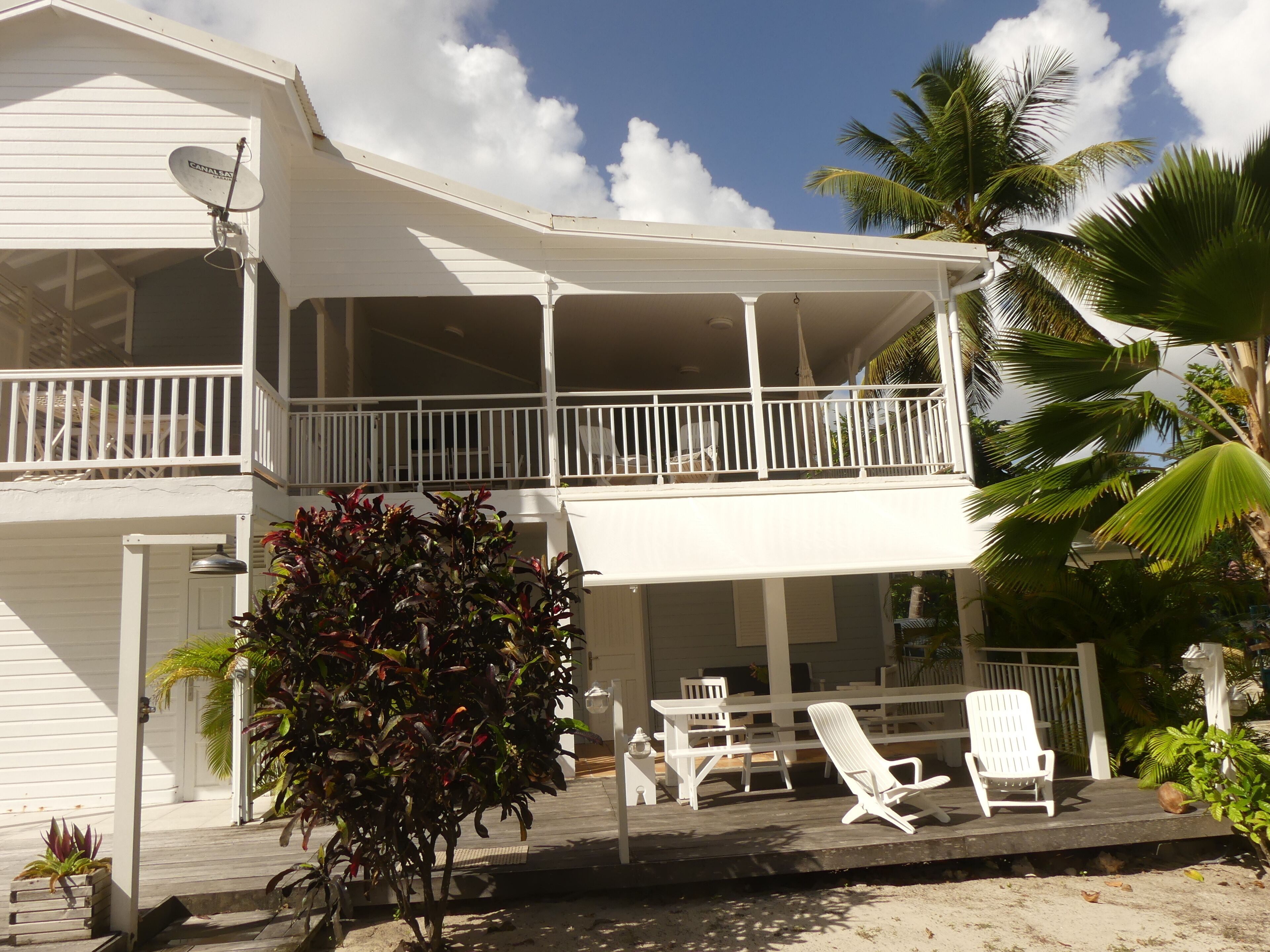 A two-story house with a balcony, outdoor furniture, and a small garden.