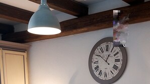 A bedroom with a bed, a wall clock, a bedside lamp, and a wooden ceiling.